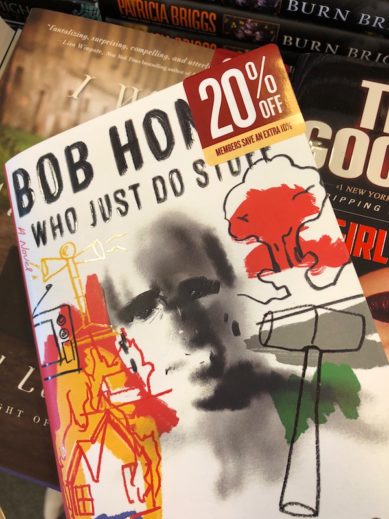 Color photograph showing the jacket of Sean Penn's book Bob Honey Who Just Do Stuff, A Novel, on top and in front of other recently released books. A sticker attached to the top right corner reads 20% off and in smaller print Members Save an Extra 10%.