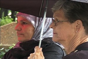 Color image of two "Women in Black" under a black umbrella, from "Vigil," the short film by Mignon & Wolf Naegeli about Women in Black Knoxville.