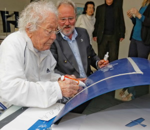 Color photograph of Hans Erni signing the engine cowling, Oscar Schwenk standing next to him.